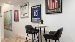Uma sala de jantar com mesa e cadeiras, adornada com objetos de coleção esportiva nas paredes, e um piso com padrão losango.