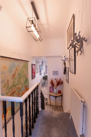 A hallway with a map, framed pictures, a sculpture, and a radiator. - Cosy flat |Center of Southend | Parking | Sleeps 4 - Pass the Keys (Southend-on-Sea)