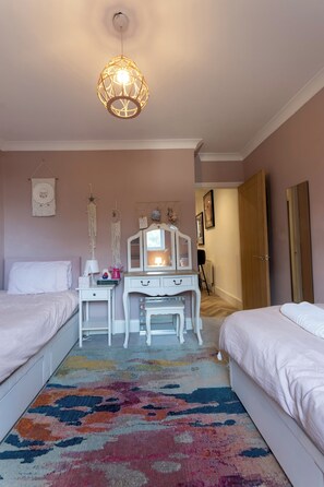 Una camera da letto con due letti, una cassettiera, uno specchio e un lampadario.