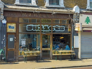 Fachada de una tienda con un letrero que dice W.J. HYDE LTD y un área de estar exterior con mesas y sillas.