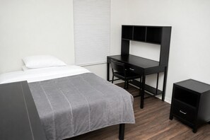 A bedroom with a bed, a desk, and a nightstand. - Spacious 4-bedroom apartment with AC in beautiful Gainesville. (Gainesville)