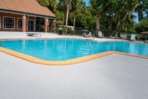 A swimming pool with a tiled deck, surrounded by a fence and palm trees. - Spacious 4-bedroom apartment with AC in beautiful Gainesville. (Gainesville)