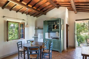 Une cuisine rustique avec des poutres en bois, une table à manger avec des chaises et un buffet vert.
