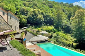 A pool area with a stone building, outdoor seating, and lush greenery. - Apartment with pool and sauna in Tuscan farmhouse (Pistoia)