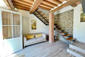 A modern living space with a staircase, a sofa, and a door leading to another room. - Apartment with pool and sauna in Tuscan farmhouse (Pistoia)