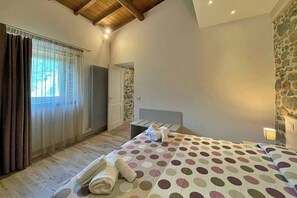 Un dormitorio con cama, radiador, pared de piedra y ventana con cortinas.