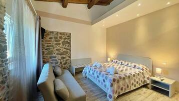 Una camera da letto con un letto, un comodino, un divano e un muro in pietra.