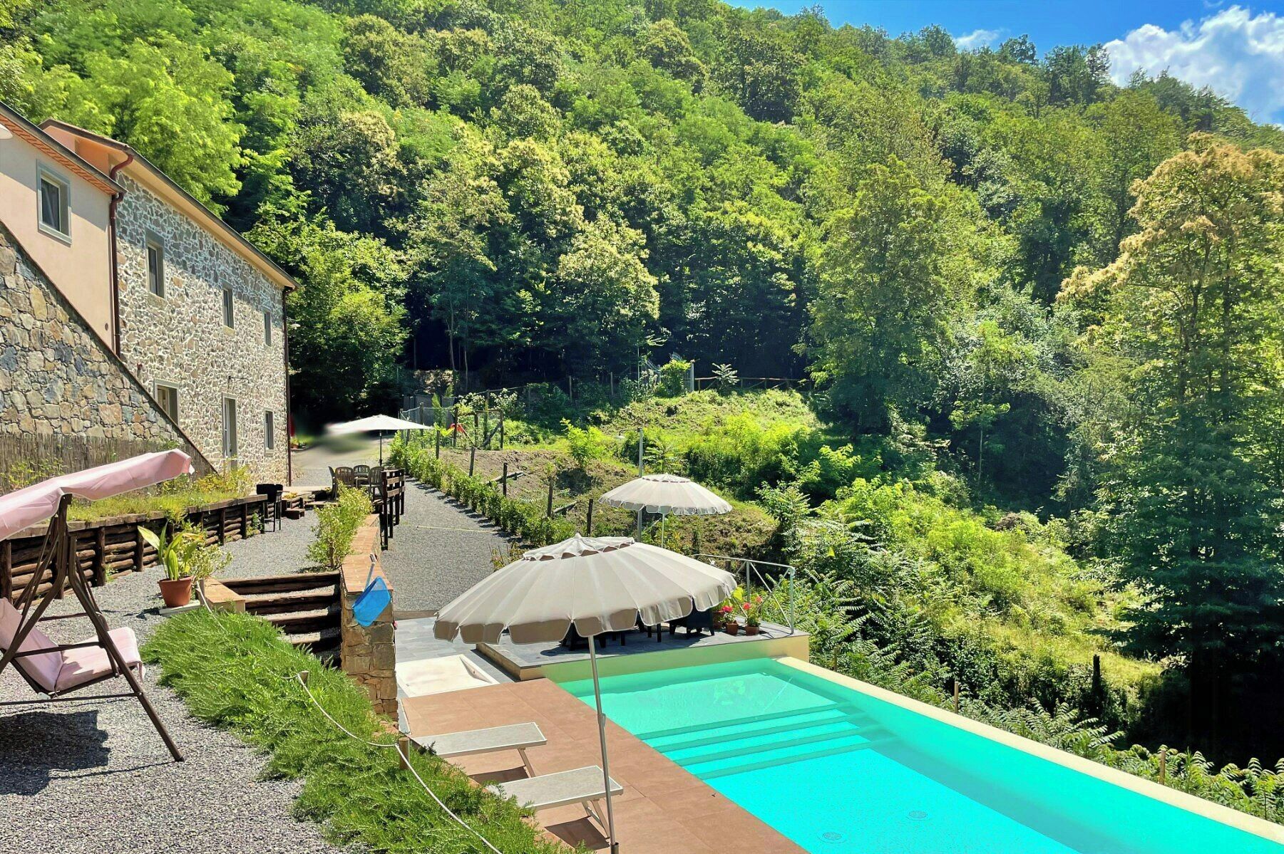 A swimming pool with a stone building and outdoor seating area.