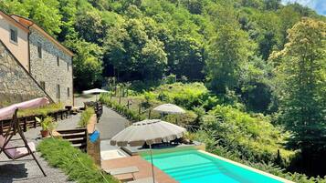 A swimming pool with a stone building and outdoor seating area.