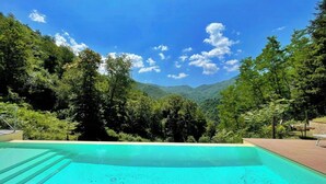 En swimmingpool med utsikt över en skogsklädd dal och berg.