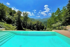 Una piscina con vistas a un valle arbolado y montañas.