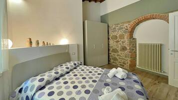 Une chambre à coucher avec un lit, une armoire, un radiateur et un mur en pierre.