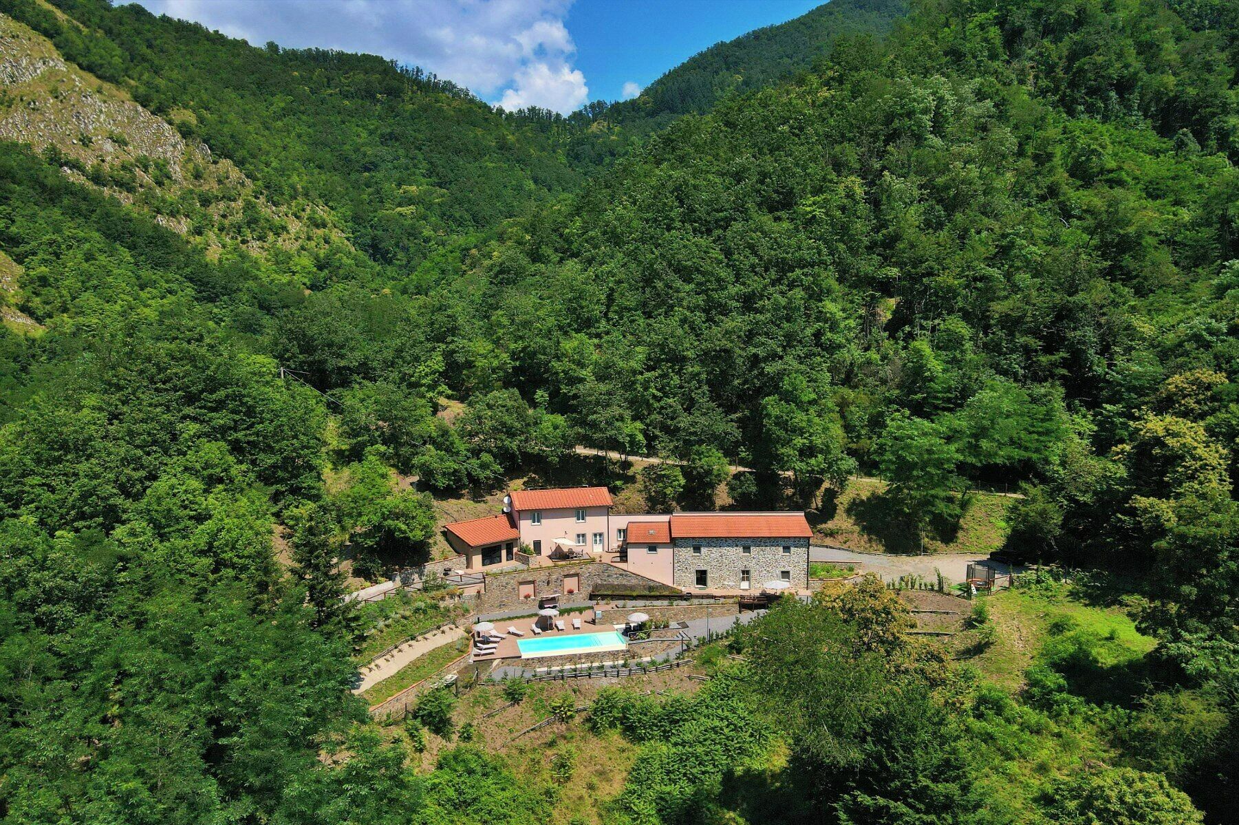 Une maison de montagne avec une piscine et plusieurs bâtiments.