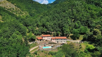 Une maison de montagne avec une piscine et plusieurs bâtiments.