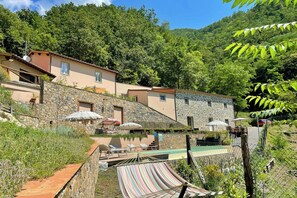 A stone building with a pool, outdoor seating, and a hammock.