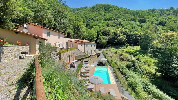 Una propietat a la vella amb piscina, mobiliari d'exterior i un mur de pedra.