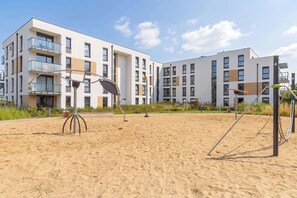 Un edifici d'apartaments modern amb nombroses galeries i una zona de platja amb equipament esportiu.