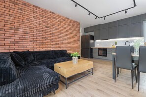 A modern kitchen with grey cabinets, a black refrigerator, and a wooden dining table with chairs. - Spacious Apartment with Garden | 2 Bedrooms | Parking (Pogórze)
