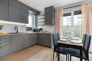 Uma cozinha moderna com armários cinza, bancada de madeira e um espaço de refeições com mesa e cadeiras.