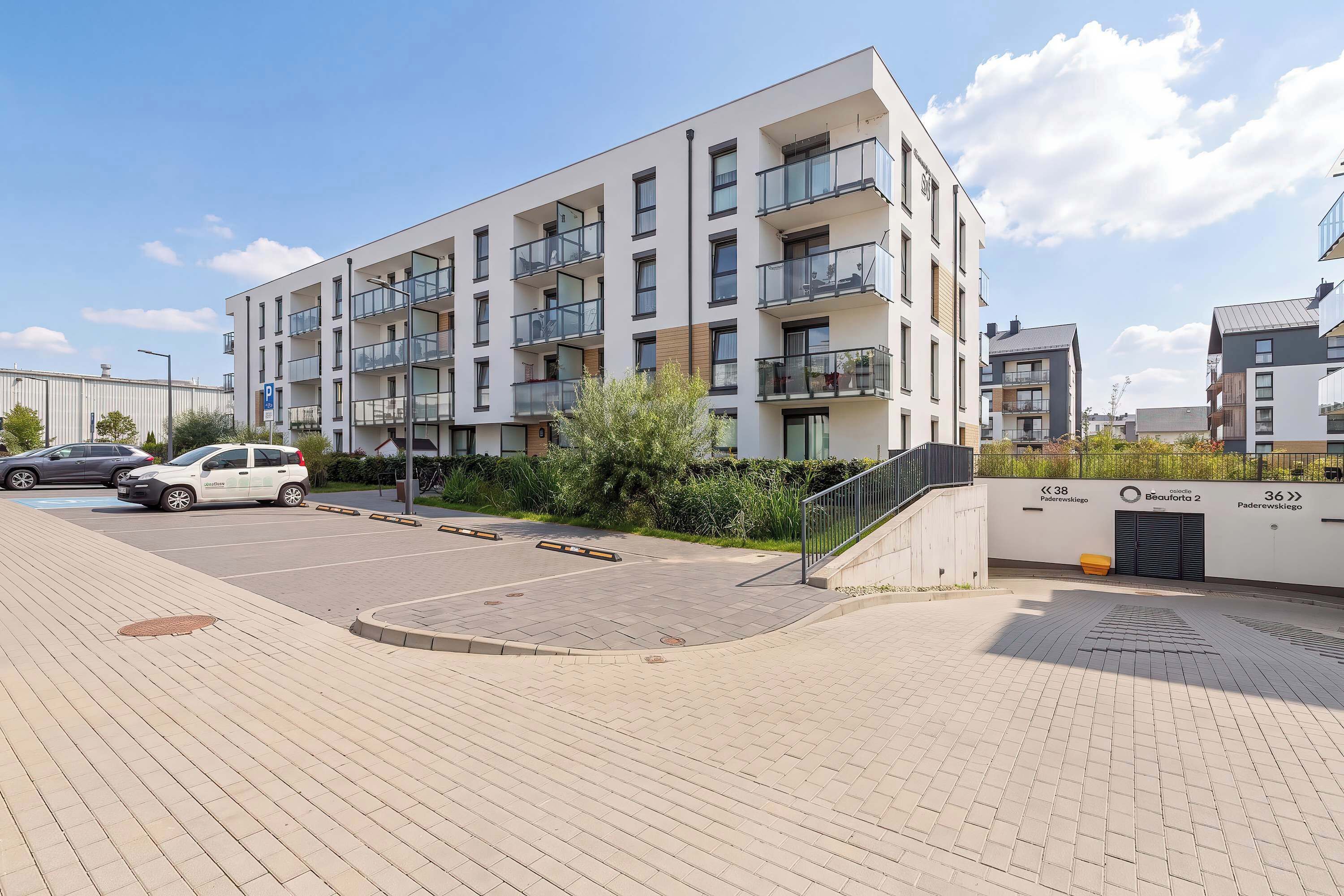 Un edificio residenziale a più piani con balconi, un'area parcheggio e un cielo sereno.
