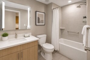 Ein modernes Badezimmer mit Waschbecken, Toilette, Dusche und einem gerahmten Bild an der Wand.