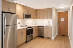 Eine moderne Küche mit Edelstahlgeräten, Holzschränken und einer weißen Arbeitsplatte.