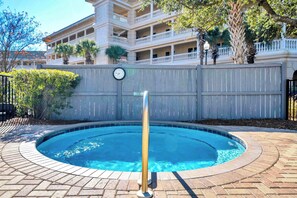 A swimming pool with a wooden deck, a fence, and a clock on the wall. - Dream Sweet by Stay on 30a (Seacrest Beach)
