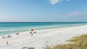 A beach with white sand, a few beach chairs, and a colorful umbrella. - Dream Sweet by Stay on 30a (Seacrest Beach)