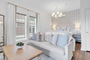 A modern bedroom with a large bed, a bedside table with a lamp, and a window with blinds. - Dream Sweet by Stay on 30a (Seacrest Beach)