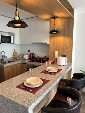 A modern kitchen with a granite countertop, two pendant lights, and a wooden ceiling. - Charming 1-bedroom apartment in pleasant Concepción (Concepción)