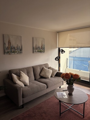A living room with a sofa, a coffee table, and two paintings on the wall. - Charming 1-bedroom apartment in pleasant Concepción (Concepción)