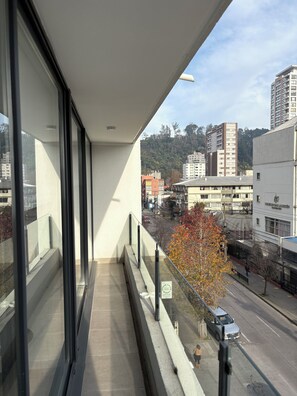 A balcony with a view of a cityscape, including buildings and a tree with autumn leaves.