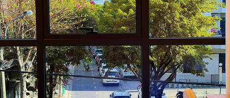 A room with a large window overlooking a street with parked cars and trees.