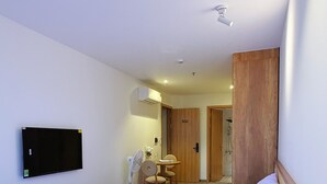 A hotel room with a bed, a wooden table, a desk, a chair, a TV, and an air conditioning unit. - La Van Residence (Da Nang)