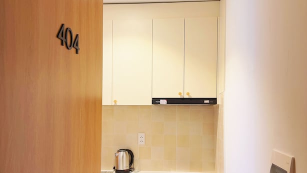 A modern kitchen with wooden cabinets, a countertop, and a kettle. - La Van Residence (Da Nang)