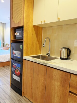 A compact kitchen with a sink, a kettle, and a refrigerator. - La Van Residence (Da Nang)