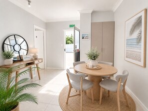 Un comedor moderno con una mesa redonda, sillas tapizadas en gris y un espejo grande.