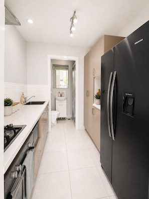 Een moderne keuken met een zwarte koelkast, witte kasten en een roestvrijstalen spoelbak.