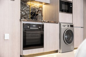 Eine moderne Küche mit integrierten Geräten, darunter ein Backofen, eine Mikrowelle und eine Waschmaschine.