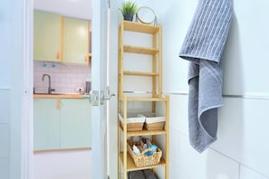 Eine Küche mit hellgrünen Schränken, einem Holzboden mit Körben und einem Handtuch an der Wand.
