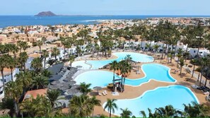 Ein Resort mit mehreren Pools, Palmen und Meerblick.