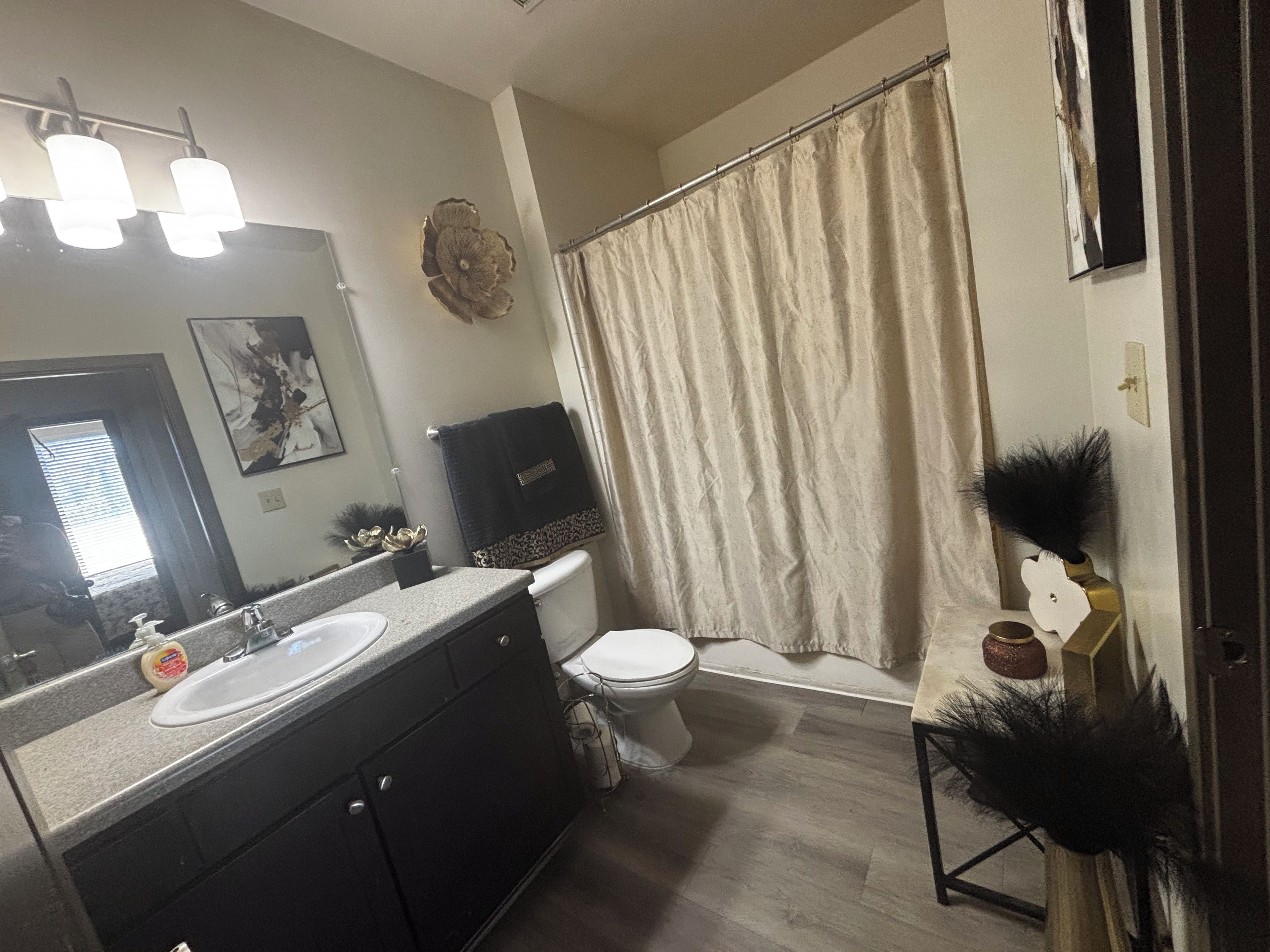 A bathroom with a double sink vanity, a toilet, a shower curtain, and a mirror.