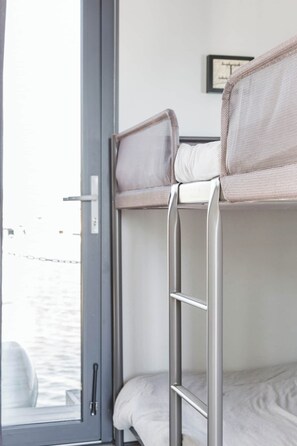 A bunk bed with a ladder, a window with a view of the water, and a framed picture on the wall. - The Homeboat Company II - PDN (Lisboa)
