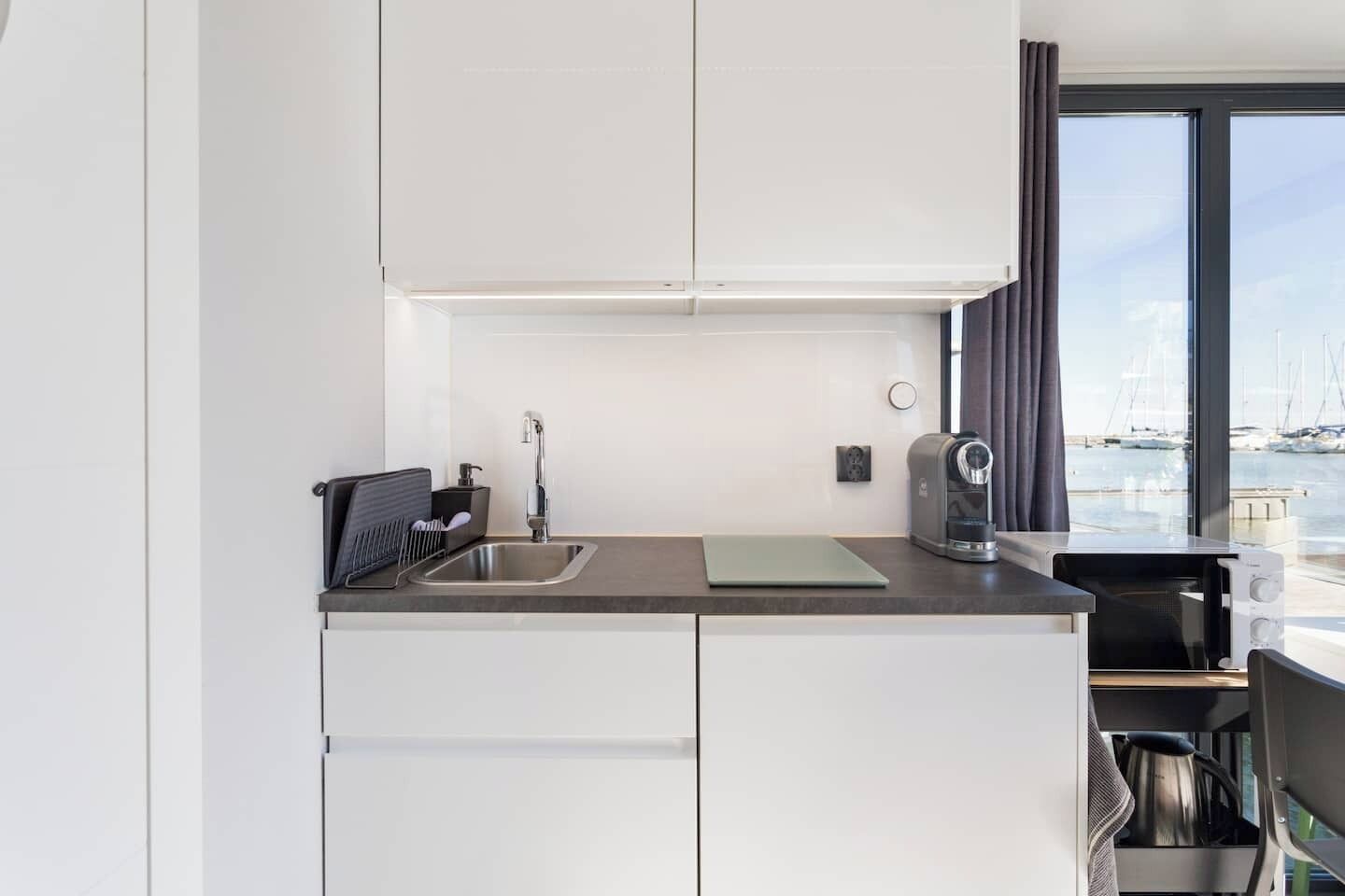 A modern kitchen with a stainless steel sink, a kettle, and a coffee maker.