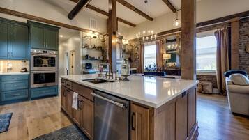 A spacious kitchen with a large island, stainless steel appliances, and wooden beams on the ceiling.