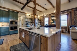 A spacious kitchen with a large island, stainless steel appliances, and wooden beams on the ceiling. - The Full Proof Penthouse in Downtown Bardstown - Walking to Restaurants & Shops! (Bardstown)