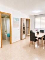 Una habitación con mesa de comedor, sillas, zona de ducha y un armario con cajones.