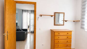 Un dormitorio con un aparador de madera, una cama, un espejo y una puerta que da a una sala de estar.