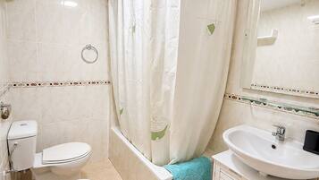 Un baño con inodoro, bañera y lavabo.