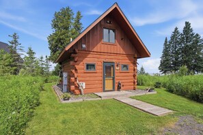 A log cabin with a wooden exterior, a front door, and a small porch area.